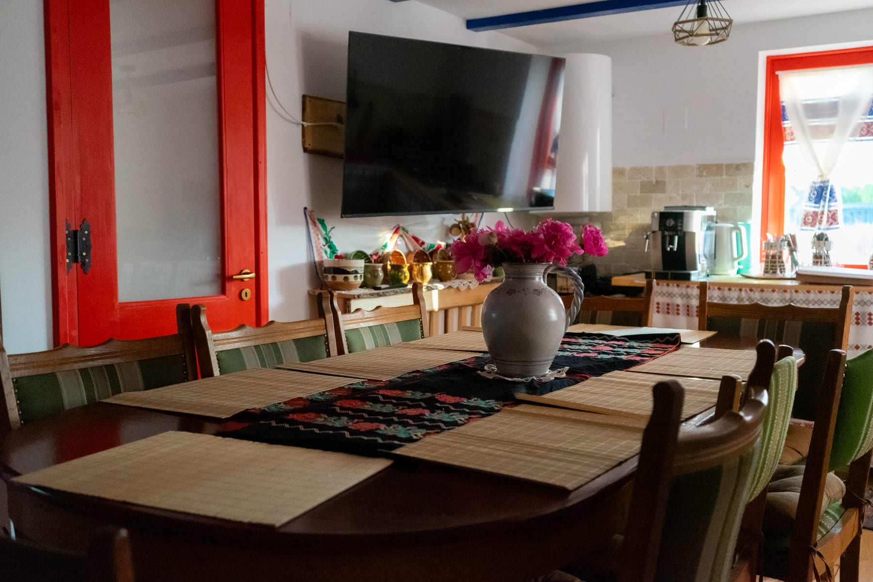 Sala de mese a casei cu masă lungă de lemn și ferestre spre curte, pentru evenimente la interior
