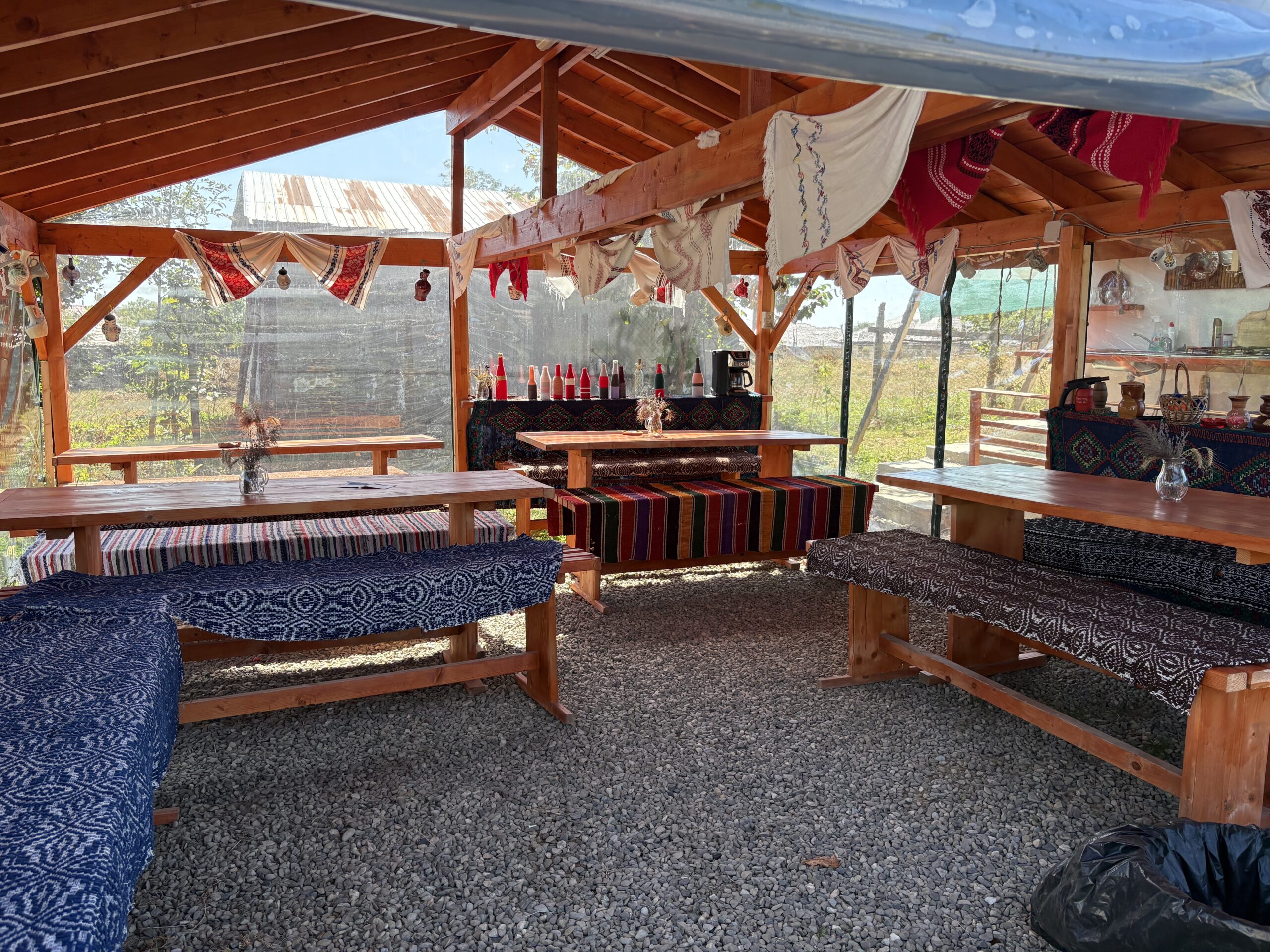 Oaspeți pe iarbă la marginea pădurii din Poiana cu Cetate, cu coșuri de picnic și pălării de paie, în curtea Căsuței cu Maci